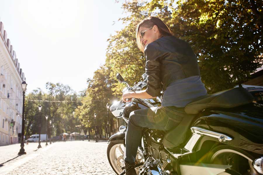 Fotografía de una chica joven, vista de espaldas, subida en una moto.