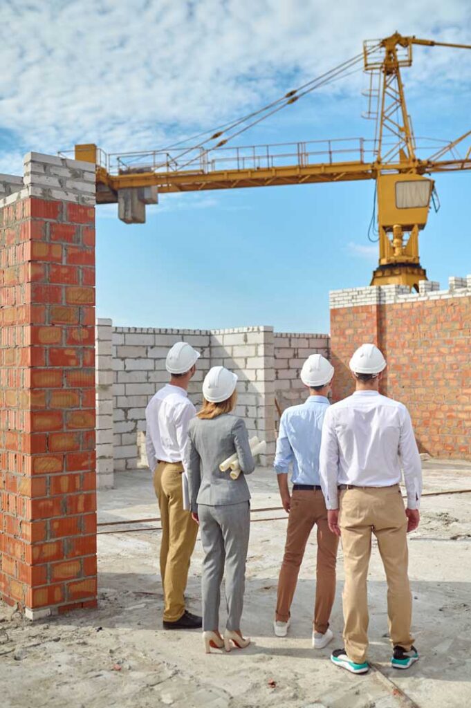Fotografía de un equipo de directores d eobra con cascos visitando una obra de construcción.