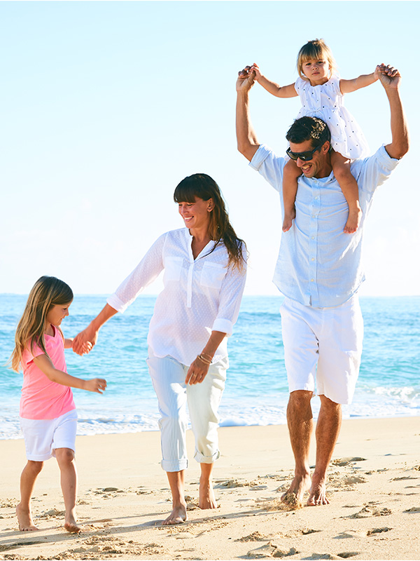 Familia feliz con dos niñas pasea por la playa.