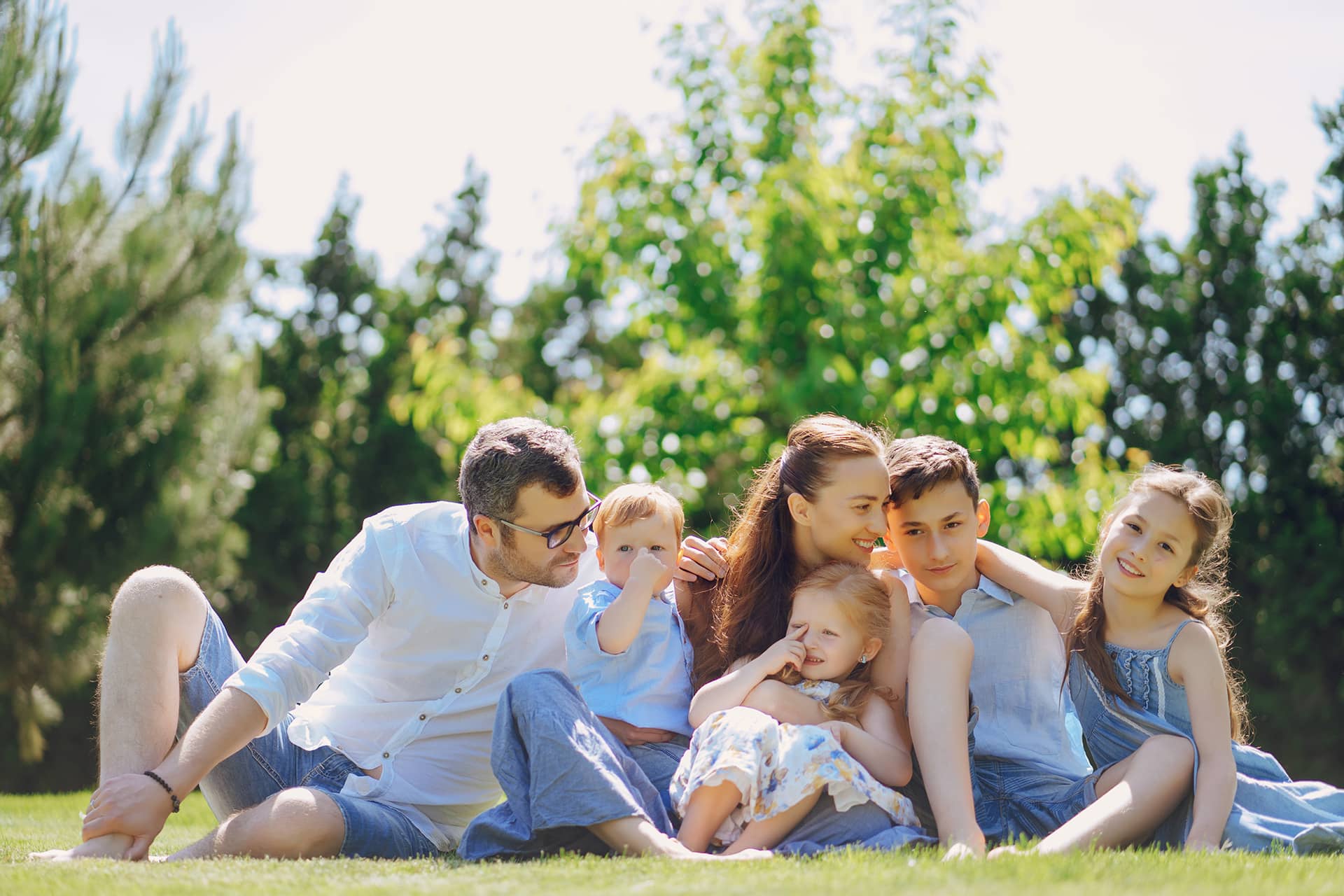 Fotografía de una familia feliz en un campo verde con cuatro hijos.